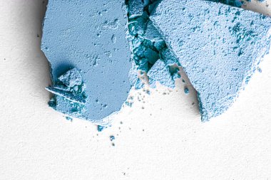 Makyaj paleti olarak mavi far pudrası beyaz arka planda izole edilmiş, ezilmiş kozmetik ve güzellik dokusu