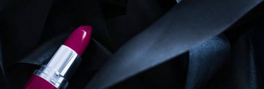 Siyah ipek arka planda mor ruj, lüks makyaj ve güzellik.