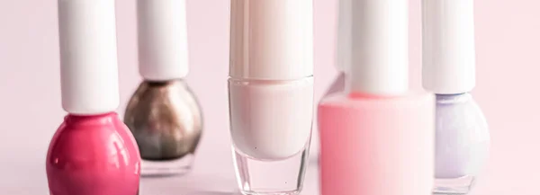 Nail polish bottles on blush pink background, beauty brand