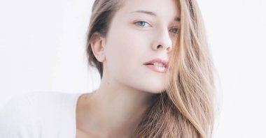 Genç bir kadının güzel yüzü, doğal makyaj görünüşü, cilt bakımı ve saç bakımı.