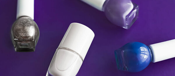 Nail polish bottles on dark purple background, beauty brand
