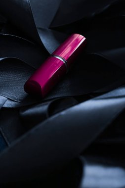 Siyah ipek arka planda mor ruj, lüks makyaj ve güzellik.