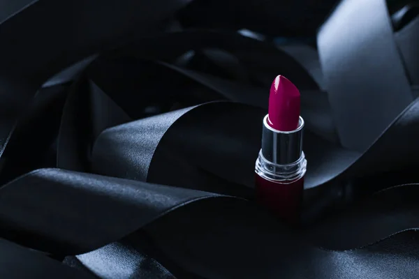 Batom roxo sobre fundo de seda preta, maquiagem de luxo e cosméticos de beleza — Fotografia de Stock