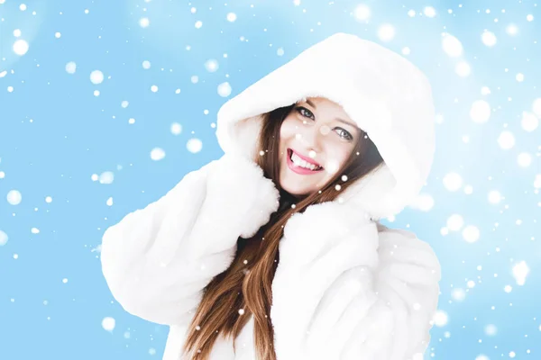 Świąteczne i zimowe wakacje portret młodej kobiety w białym płaszczu z kapturem, śnieg na niebieskim tle, moda i styl życia — Zdjęcie stockowe