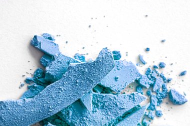 Makyaj paleti olarak mavi far pudrası beyaz arka planda izole edilmiş, ezilmiş kozmetik ve güzellik dokusu