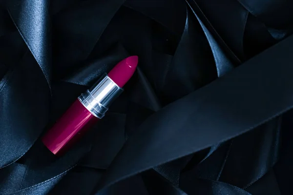 Purple lipstick on black silk background, luxury make-up and beauty cosmetic