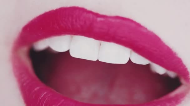 Labios con lápiz labial rosa y dientes blancos sonriendo, macro primer plano de sonrisa femenina feliz, salud dental y maquillaje de belleza — Vídeos de Stock