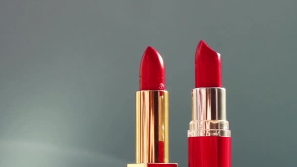 Дві розкішні червоні помади на кольоровому фоні та блискучі спалахи світла, розкішний макіяж та святкова косметика для бренду краси — стокове відео