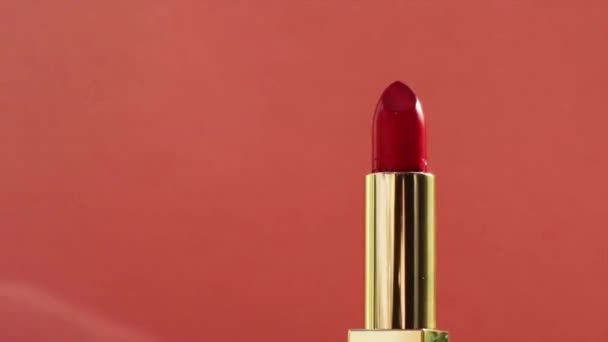 Шикарная красная помада в золотой трубке и яркие вспышки света, роскошный косметический продукт и праздничная косметика для бренда красоты — стоковое видео