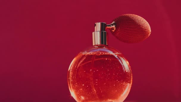 Sticlă de parfum de epocă și erupții luminoase pe fundal roșu, parfum plin de farmec ca produs de parfumerie de lux pentru marca cosmetică și de frumusețe — Videoclip de stoc