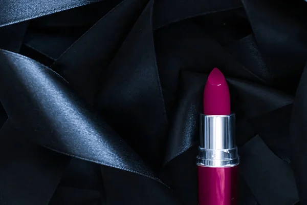 Lápiz labial púrpura sobre fondo de seda negro, maquillaje de lujo y cosméticos de belleza — Foto de Stock