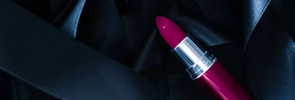 Purple lipstick on black silk background, luxury make-up and beauty cosmetic