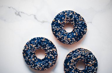 Şekerli donutlar, mermer masa zemininde tatlı tatlılar, lezzetli atıştırmalıklar olarak çörekler, blog, menü ya da yemek kitabı tasarımı için en üst düzey yiyecek markası düzlüğü