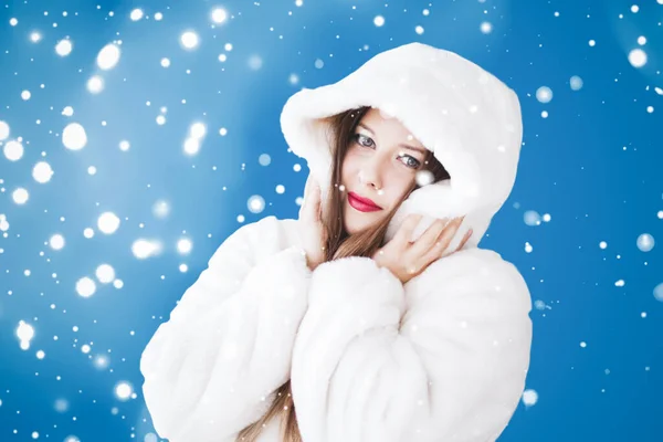 Mutlu noeller ve kış tatili portresi beyaz kapüşonlu kürklü genç kadın, mavi arka planda kar, moda ve yaşam tarzı — Stok fotoğraf