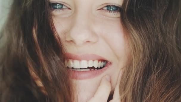 Hermosa cara de mujer sonriente con maquillaje natural, piel brillante y sonrisa dentada saludable, retrato de cerca y cabello castaño barrido por el viento — Vídeo de stock