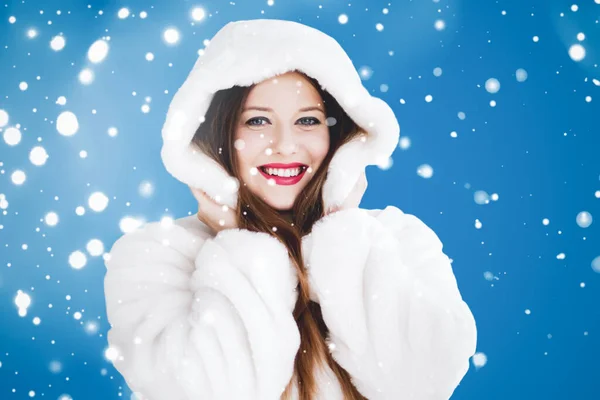 Szczęśliwego Bożego Narodzenia i zima wakacje portret młodej kobiety w białym płaszczu z kapturem, śnieg na niebieskim tle, moda i styl życia — Zdjęcie stockowe