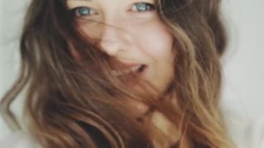 Güzel, gülümseyen bir kadın yüzü, parlak bir ten ve sağlıklı dişli bir gülümseme, yakın plan portre ve rüzgarlı kahverengi saçlar.