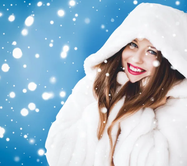 Feliz Natal e férias de inverno retrato de jovem mulher de casaco de pele com capuz branco, neve no fundo azul, moda e estilo de vida — Fotografia de Stock