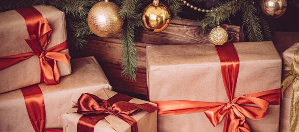 Hediye kutuları ve altın Noel ağacı, tatil evi dekorasyonu olarak köy tarzı hediyeler ve dekorlar.