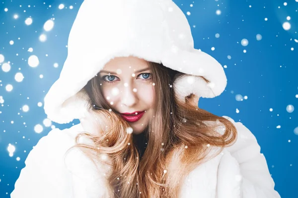 Feliz Natal e férias de inverno retrato de jovem mulher de casaco de pele com capuz branco, neve no fundo azul, moda e estilo de vida — Fotografia de Stock