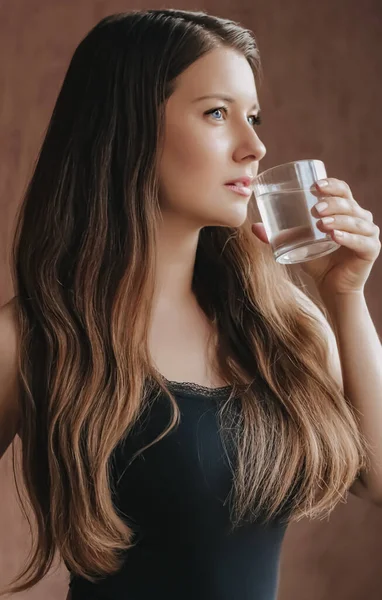Donna che beve acqua dal vetro a casa, rimane sana e idratata, dieta e benessere — Foto Stock