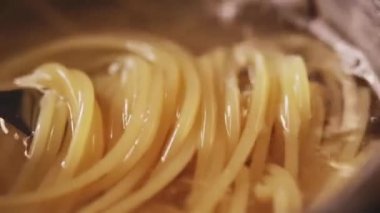 Evde gümüş kapta kaynamış suda makarna pişirmek, ev yapımı konfor yemeği olarak tam buğday İtalyan spagettisi, organik malzeme ve online aşçılık sınıfı konsepti.