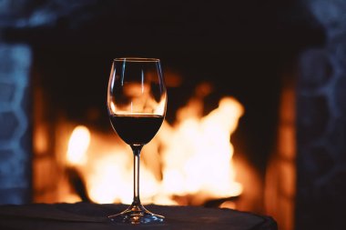 Şöminenin önünde kırmızı şarap, evde rahatlatıcı bir atmosfer.