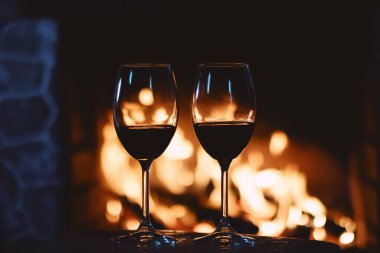 Şöminenin önünde kırmızı şarap, evde rahatlatıcı bir atmosfer.
