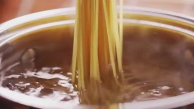 Evde gümüş kapta kaynamış suda makarna pişirmek, ev yapımı konfor yemeği olarak tam buğday İtalyan spagettisi, organik malzeme ve online aşçılık sınıfı konsepti.