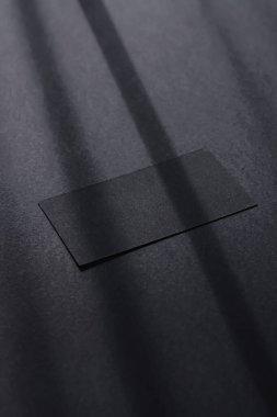 Koyu renk düz arka plan ve güneş ışığı gölgeleri üzerine siyah kartvizit, lüks markalaştırma yatağı ve model kimlik tasarımı