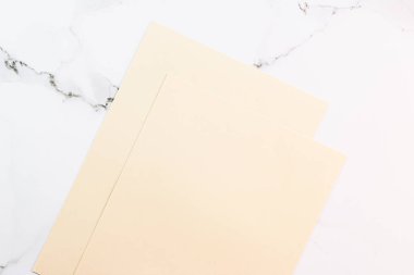 Beyaz mermer arka plan üzerine bej renkli A4 kağıtları ofis kırtasiyesi düz yatak, lüks markalaşma yatağı ve model kimlik tasarımı