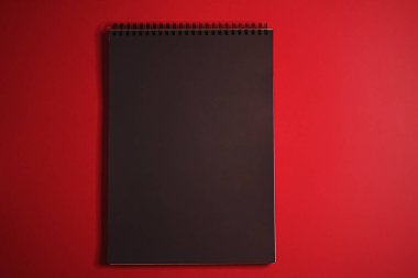 Kırmızı arkaplanda ofis kırtasiyesi olarak siyah defter, lüks markalaştırma dairesi ve model kimlik tasarımı