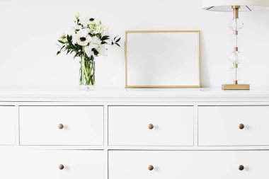Beyaz mobilyalar, lüks ev dekorasyonu ve maket tasarımı üzerine altın yatay çerçeve ve taze çiçek demeti