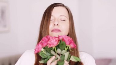 Bayram hediyesi olarak gül buketi olan mutlu kadın, gülümseyen ve koklayan çiçekler, insanlar ve güzellik