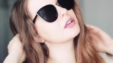 Moda, aksesuar ve insan konsepti olarak beyaz Avrupalı bir modelin şık güneş gözlüğü takan ve gülümseyen güzel yüzü olan şık bir kadın.