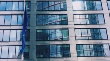 Avrupa Birliği bayrağı, AB Parlamentosu, Komisyon ve Konsey 'in sembolü modern şirket binası önünde dalgalanıyor