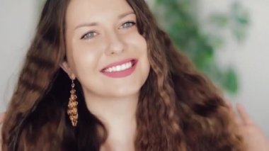 Uzun altın küpeler takan, gülümseyen, altın mücevher, moda ve mücevher reklamlarında poz veren Avrupalı beyaz bir kadın.