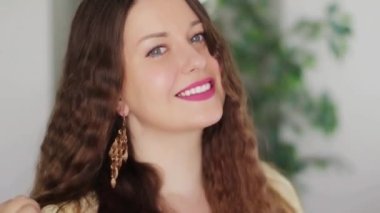 Uzun altın küpeler takan, gülümseyen, altın mücevher, moda ve mücevher reklamlarında poz veren Avrupalı beyaz bir kadın.