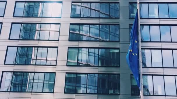Bandeira da União Europeia acenando em frente ao moderno edifício de escritórios corporativos, símbolo do Parlamento Europeu, Comissão e Conselho — Vídeo de Stock