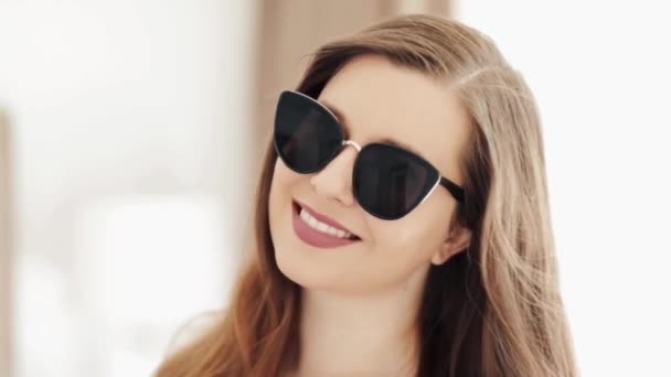Hermosa mujer de negocios que lleva gafas de sol elegantes y sonriente, retrato de la cara de belleza de un modelo europeo caucásico como concepto de moda, accesorios y gente de negocios — Vídeo de stock