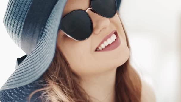 Giovane donna sorridente che indossa occhiali da sole alla moda e cappello da sole estivo, vacanza felice e destinazione di vacanza al mare, viaggi di lusso e persone all'aperto — Video Stock