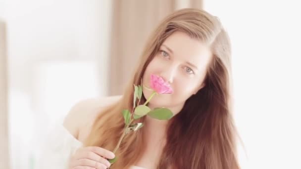 Atractiva mujer joven con un hermoso jardín rosa rosa flor, belleza natural retrato de una modelo europea caucásica como el bienestar, cuidado de la piel y las personas — Vídeo de stock