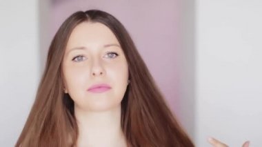 Işıl ışıl sağlıklı saçları, uzun saç stili ve doğal makyajı olan güzel bir kadın. Saç bakım konsepti, mutlu bir gülümseme ve güzellik ve sağlığa karşı olumlu bir duygu.