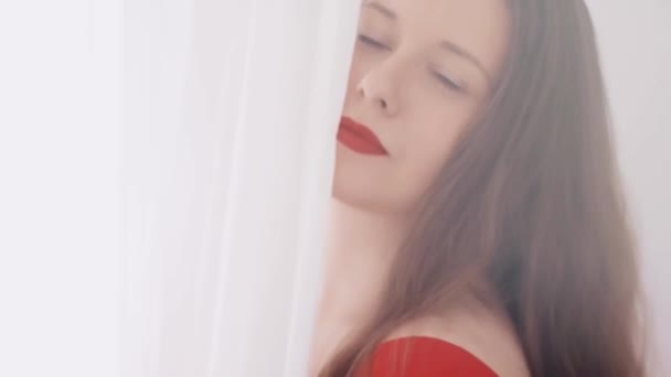 Hermosa mujer morena sonriendo, posando y bailando, luz brillante desde una ventana o puerta y cortinas blancas en el fondo, estilo de vida femenino y belleza natural — Vídeos de Stock