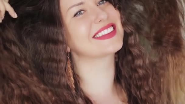 Hermosa mujer con pelo rizado brillante largo y saludable, modelo morena con rizos ondulados y sin calor peinado, perfecta sonrisa de dientes blancos, retrato de la cara de belleza y cuidado del cabello orgánico natural comercial — Vídeo de stock