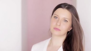 Doğal makyajlı güzel bir kadın portresi, sağlıklı parlak cilt ve uzun saç stili, pembe arka planda poz veren beyaz kadın modeli, saç estetiği ve makyaj malzemesi.