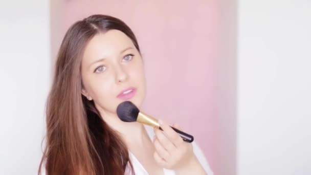 Kvinna med kosmetisk borste tillämpa makeup och leende, skönhet ansikte porträtt av kaukasisk kvinnlig modell på rosa bakgrund, naturlig make-up idé, kosmetika och hudvård produkt kommersiell — Stockvideo