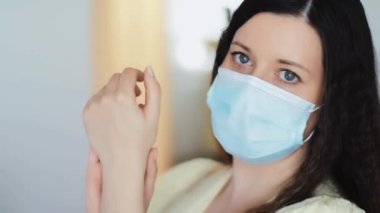 Korunaklı yüz maskeli bir kadın el yıkama deterjanı, el kremi ya da antiviral, koronavirüs salgınında hijyen olarak antibakteriyel jel, virüs enfeksiyonu önleme ve sağlık koruma ile ellerini yıkıyor.