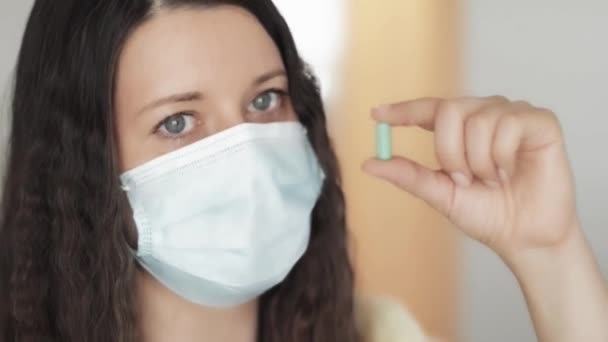 Woman in protective face mask with medicine capsule, drug medication or supplement pill for immune system and health care, virus infection treatment in coronavirus pandemic, science and healthcare — Stock Video