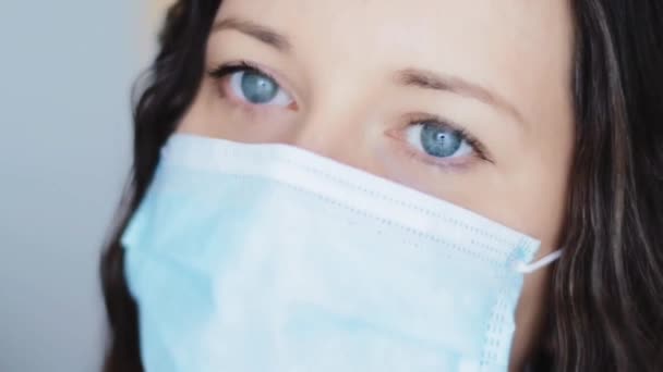 Woman with sad blue eyes in protective face mask, sadness, grief, stress and negative emotion during quarantine lockdown due to coronavirus pandemic, virus infection prevention and healthcare — Stockvideo